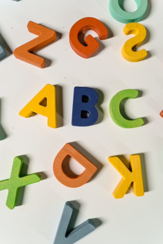 Bright, colorful wooden letters scattered on a white surface forming the alphabet.